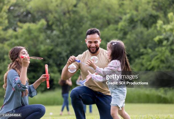 mom and dad enjoy playing with daughter in the park - aunt niece stock pictures, royalty-free photos & images