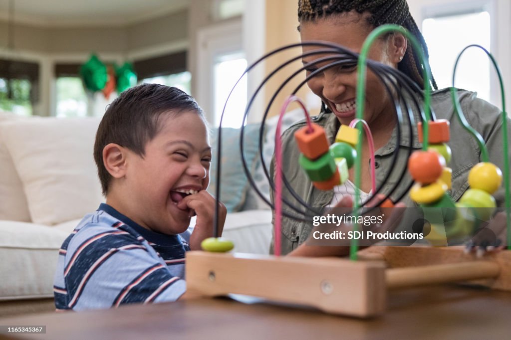 Mom and son laugh together while playing in living room