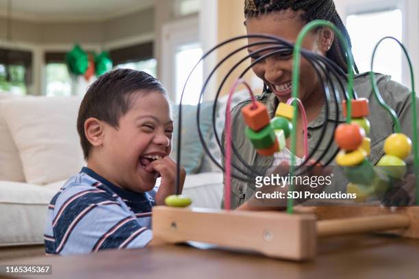 mom and son laugh together while playing in living room - disability stock pictures, royalty-free photos & images