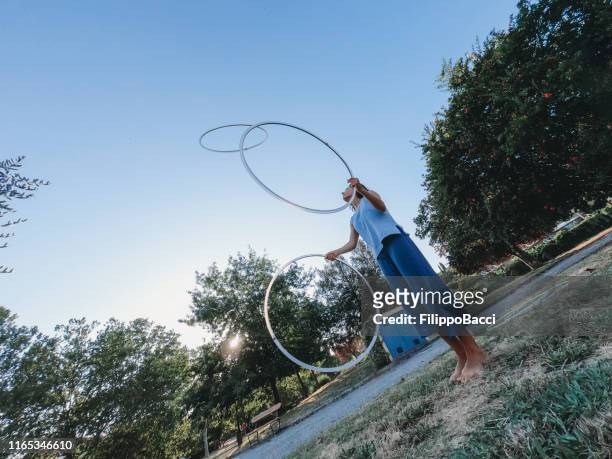 ung vuxen kvinna jonglering med hula hoop på den offentliga parken - ring toss bildbanksfoton och bilder