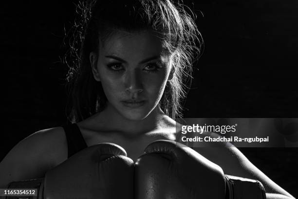 woman muay thai boxer fighting. fit young female boxer in sportswear isolated on black background. - kickboxing gloves stock pictures, royalty-free photos & images