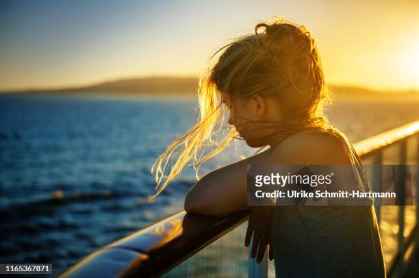 girl at railing at sunset - kreuzfahrt stock-fotos und bilder