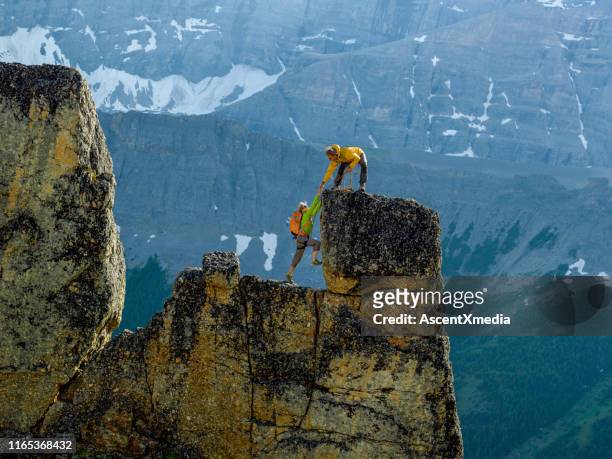 montañeros escalan rocas pasos en acantilado con cuerda - montañas rocosas canadienses fotografías e imágenes de stock