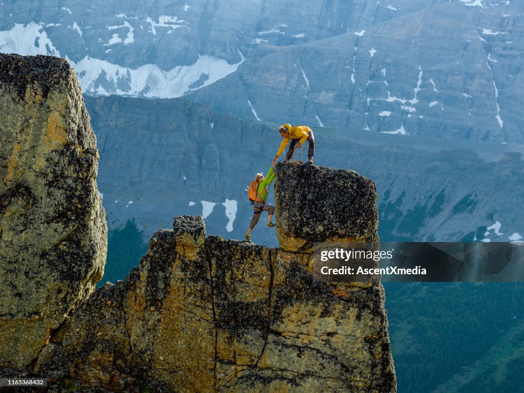 Mountaineers scale rocks steps on cliff with rope