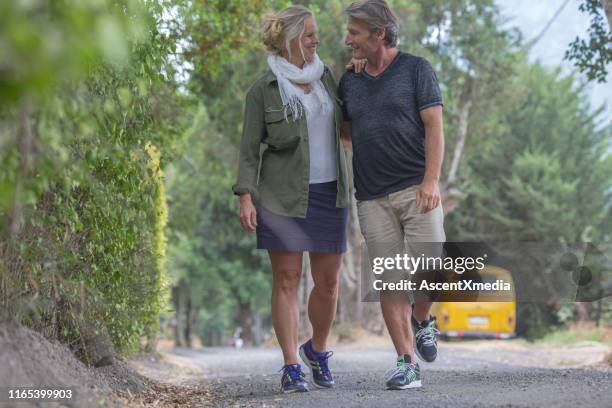 mature couple walk along country road talking - khaki shorts stock pictures, royalty-free photos & images
