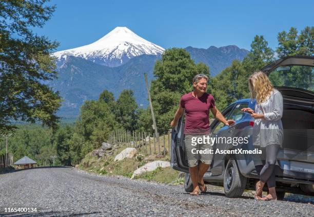 o par maduro usa a tabuleta digital fora do carro na estrada ao vulcão de osorno - osorno volcano - fotografias e filmes do acervo