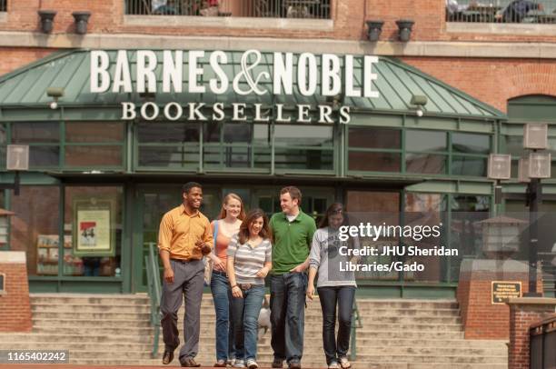 Group of Johns Hopkins University students walk down steps outside the glass-fronted entrance to a Barnes and Noble book store in the former Pratt...