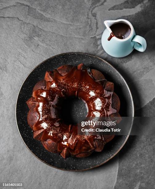 chocolate bundt cake on a plate on black background - chocolate cake stock pictures, royalty-free photos & images