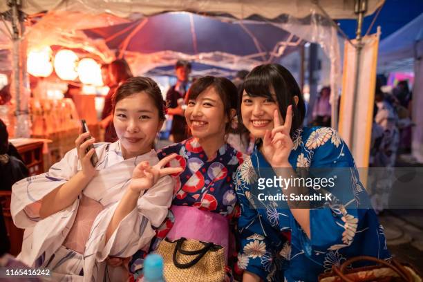 mulheres novas no yukata que toma o grupo disparado na tenda do alimento - matsuri - fotografias e filmes do acervo