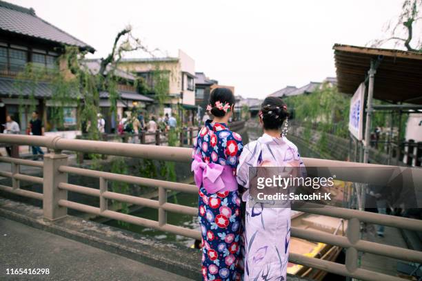 junge frauen in yukata mit blick von der brücke - yukata kimono stock-fotos und bilder