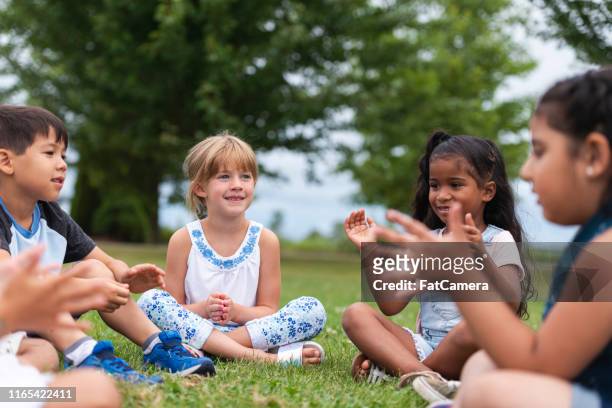 a multi-ethnic group of young children are clapping outside - summer school stock pictures, royalty-free photos & images