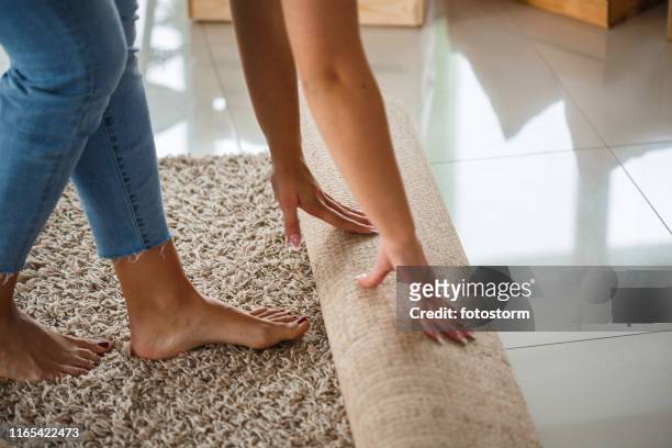 donna che rotola nuovo tappeto - posizionare foto e immagini stock