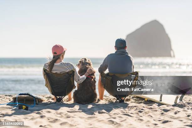 a young couple relaxing on the beach with their dog - oregon coast stock pictures, royalty-free photos & images