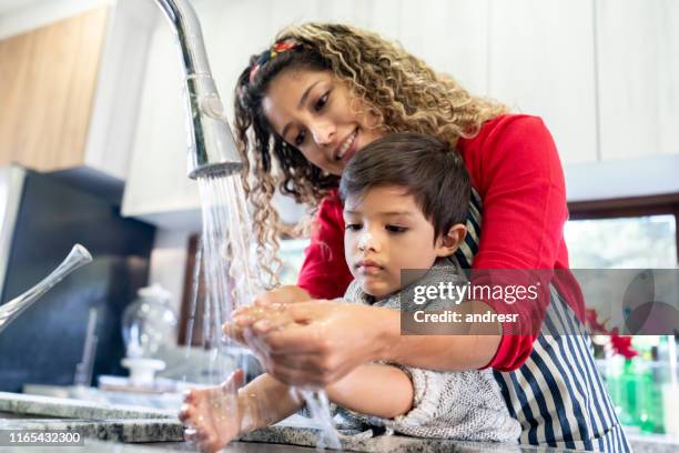 moeder helpen zoon wassen zijn hand na het maken van cookies - child washing hands stockfoto's en -beelden