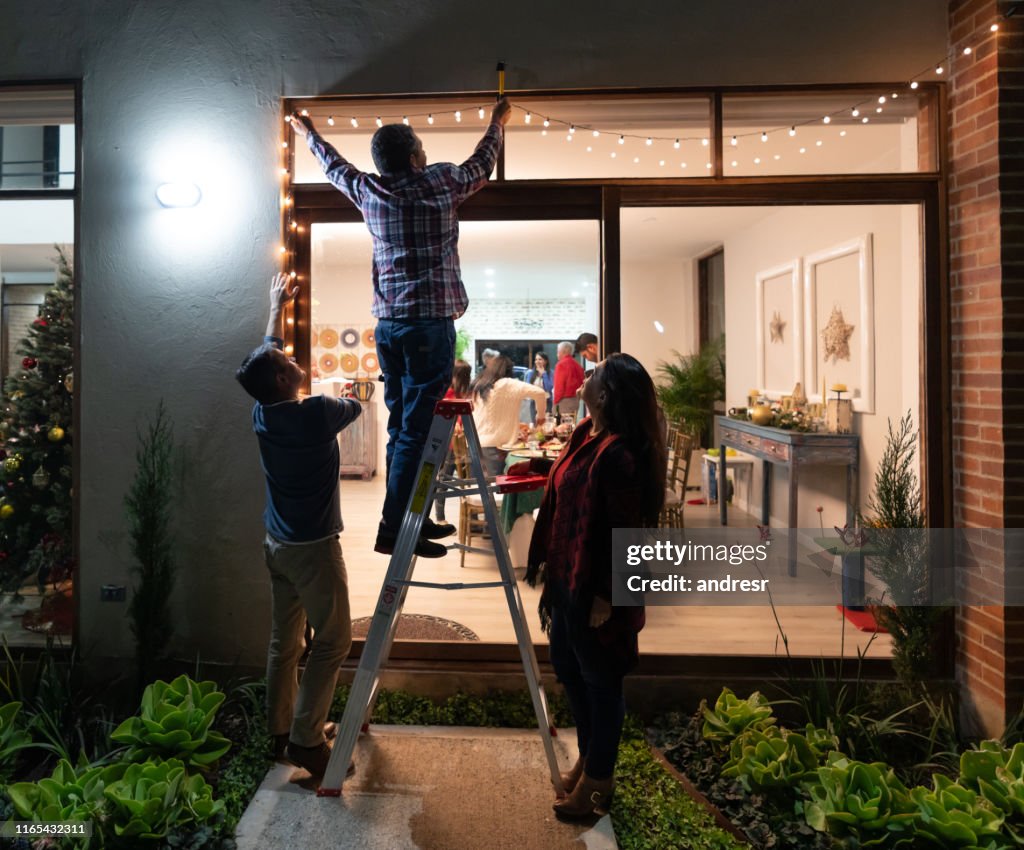 Familie schmückt das Haus für Weihnachten und hängende Lichter