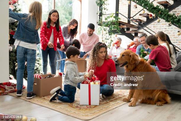 happy family decorating the house for christmas with the help of their dog - multi generational family with pet stock pictures, royalty-free photos & images