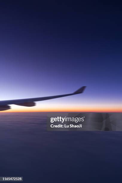 the plane flew over the clouds at sunset - plane wing stock-fotos und bilder