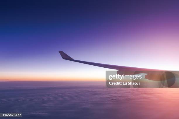 the plane flew over the clouds at sunset - plane wing stock-fotos und bilder