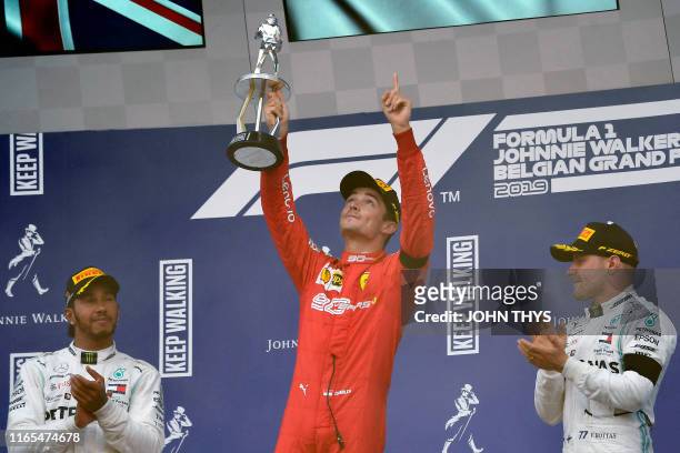 Winner Ferrari's Monegasque driver Charles Leclerc holds his trophy and gestures towards the sky in tribute to late French driver Anthoine Hubert...