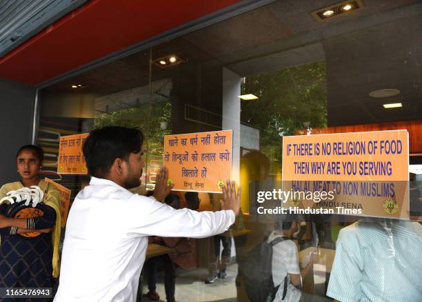 Hindu Sena activists stick posters during a protest against fast food chain McDonald for serving food compliant with Halal dietary restrictions, at...