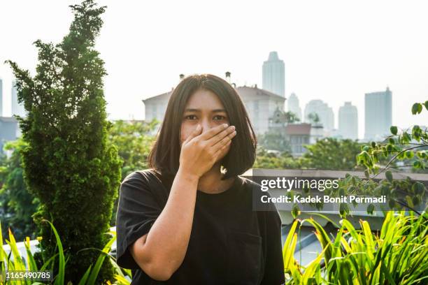 a woman is covering her nose with her hand - over mouth stock pictures, royalty-free photos & images