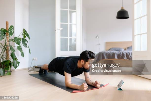 asiatischer mann nutzt digitales tablet, um die position der planken zu lehnen - acrobatic yoga stock-fotos und bilder