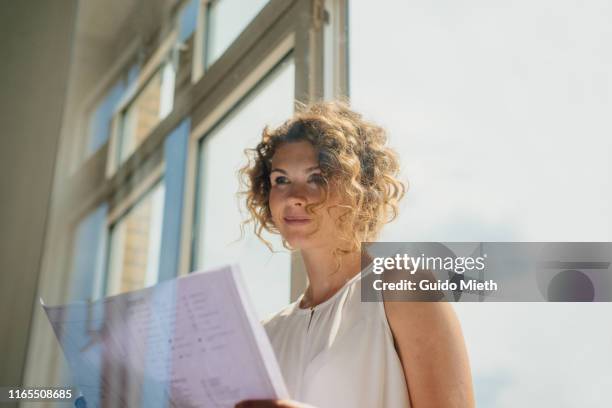 female architect holding blueprints in new office. - new business construction stock pictures, royalty-free photos & images