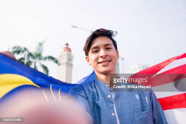 giovane che si fa selfie con la bandiera della malesia - malaysia independence day foto e immagini stock