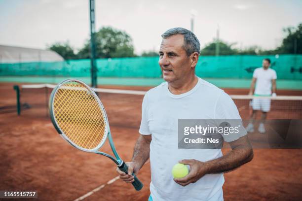 テニスラケットを持つシニア男性 - tennis coaching ストックフォトと画像