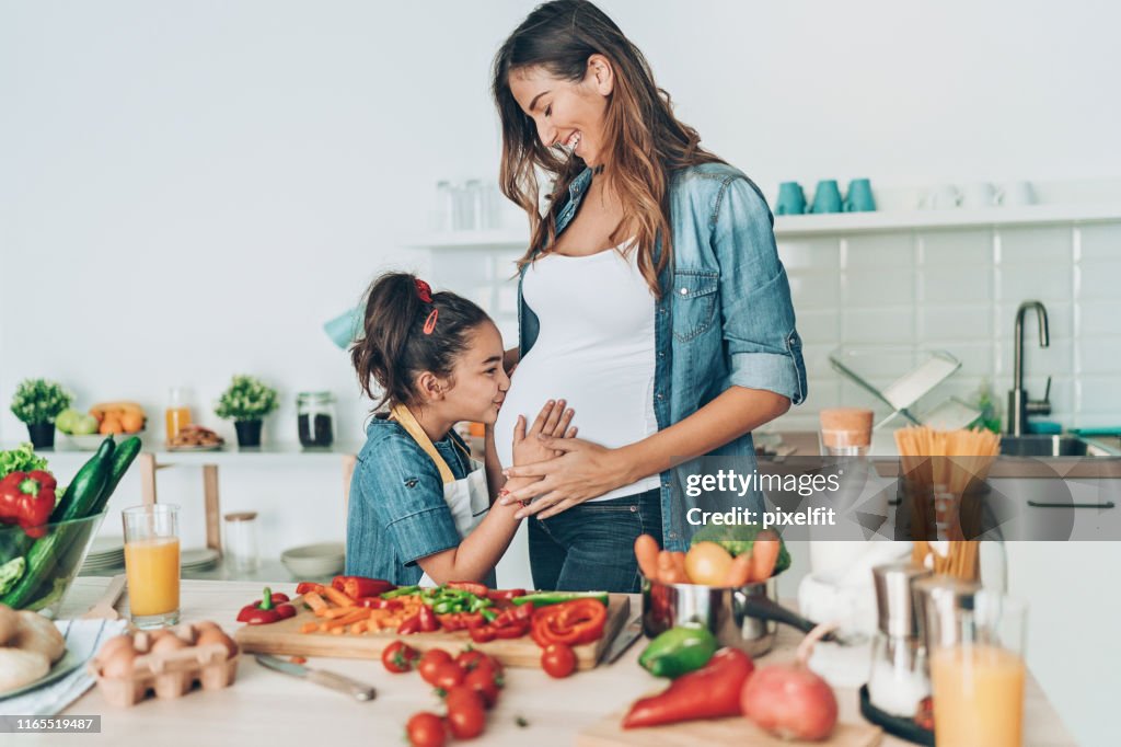 Small girl kissing her pregnant mother