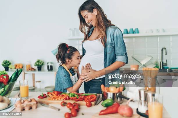 small girl kissing her pregnant mother - girly pregnant stock pictures, royalty-free photos & images