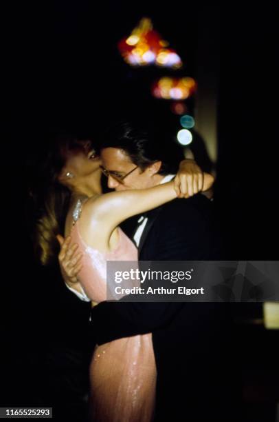 Vogue, April 01, 1974 - Model embracing a male model with multi-colored lights shining behind them. She is wearing a long evening dress of light pink...