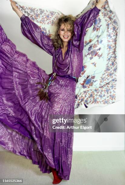 Vogue, November 01, 1977 - Model Roseanne Vela doing a high kick wearing a glittering purple silk blouse with a matching long tiered skirt with a...