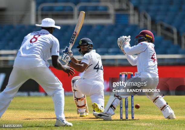 Hanuma Vihari of India hits pass Jason Holder and Jahmar Hamilton of West Indies during day 3 of the 2nd Test between West Indies and India at Sabina...