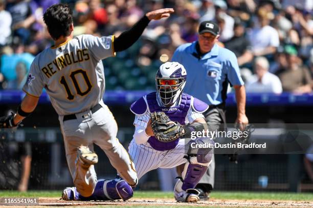 Tony Wolters of the Colorado Rockies waits to apply a tag on Bryan Reynolds of the Pittsburgh Pirates at home plate to end the top of the third...