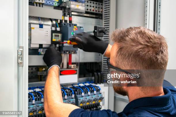 électricien travaillant au panneau électrique - technicien photos et images de collection