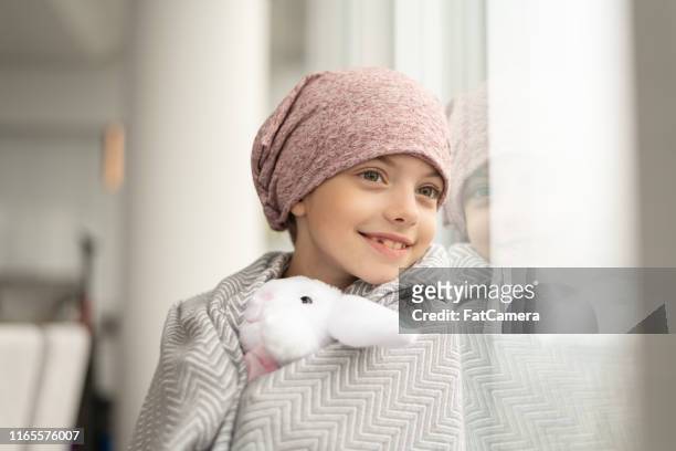 smiling girl with cancer looks out window - cancer illness stock pictures, royalty-free photos & images