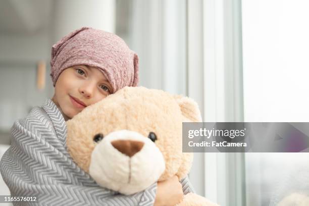 porträt eines krebskranken mädchens, das einen teddybären hält - child teddy bear stock-fotos und bilder