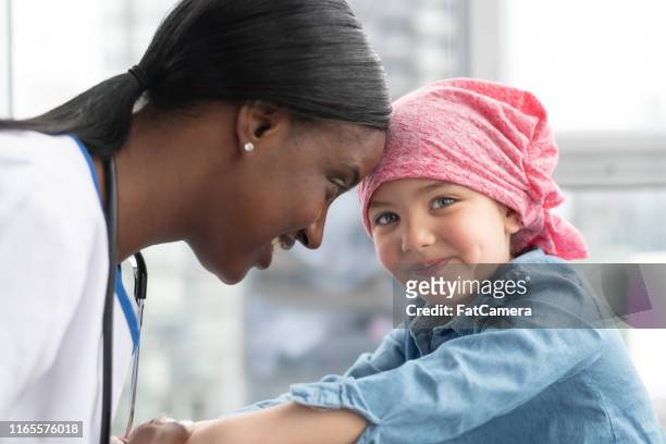 une femme réconforte sa jeune patiente atteint d'un cancer - aide patient médecin photos et images de collection