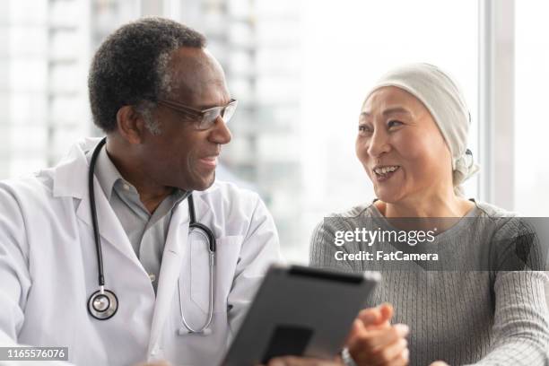 woman with cancer reviews test results with doctor - black bandana stock pictures, royalty-free photos & images