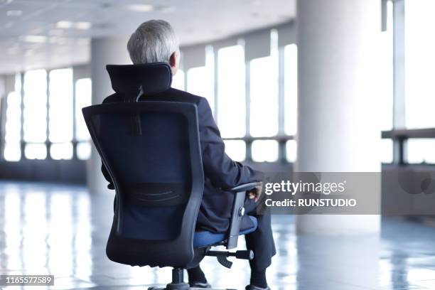 rear view of senior businessman sitting on chair in office - back of office chair stock pictures, royalty-free photos & images