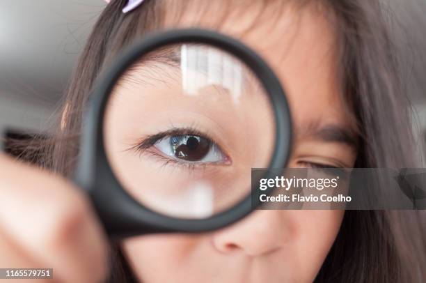 girl looking at camera through magnifying glass - heranzoomen stock-fotos und bilder