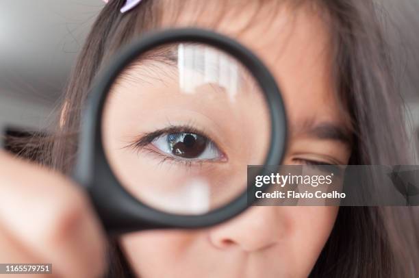 girl looking at camera through magnifying glass - inzoomen stockfoto's en -beelden