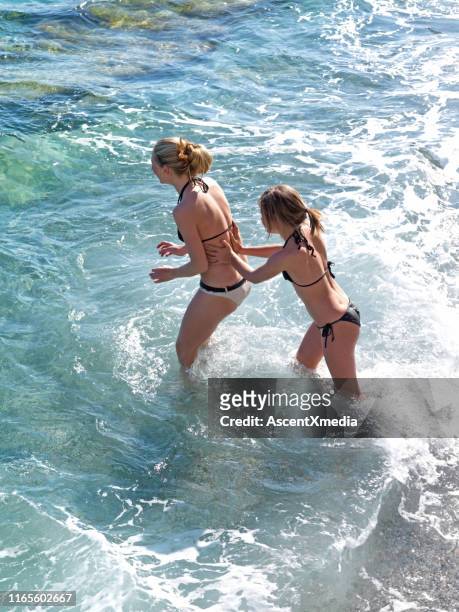 teenager girls wade out into sea - tween girls swimwear stock pictures, royalty-free photos & images