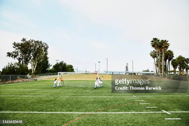 young female soccer players moving goal into place on field before practice - local soccer field stock pictures, royalty-free photos & images