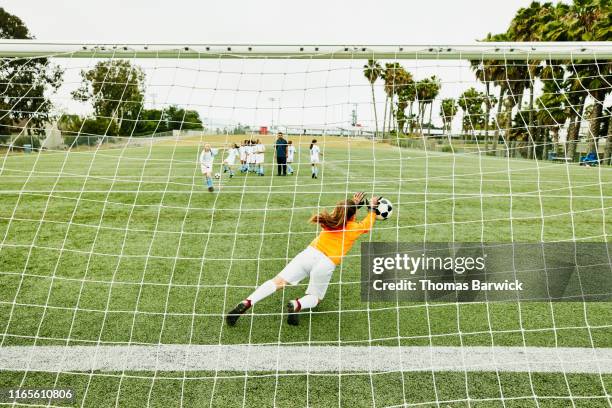 young female soccer goalie diving for shot during practice - chutar fotografías e imágenes de stock