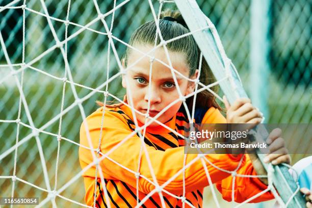 Young female soccer goalie moving goal into place before practice