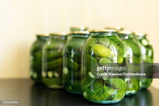 pickled cucumbers in glass jar on a gray wooden table. - cucumber leaves stock pictures, royalty-free photos & images