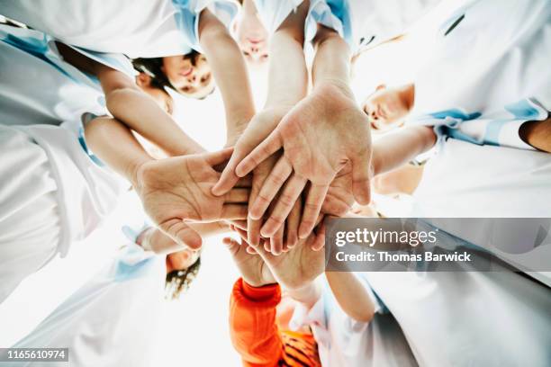 view from below of young female soccer players bringing hands together before game - youth sports team stock pictures, royalty-free photos & images