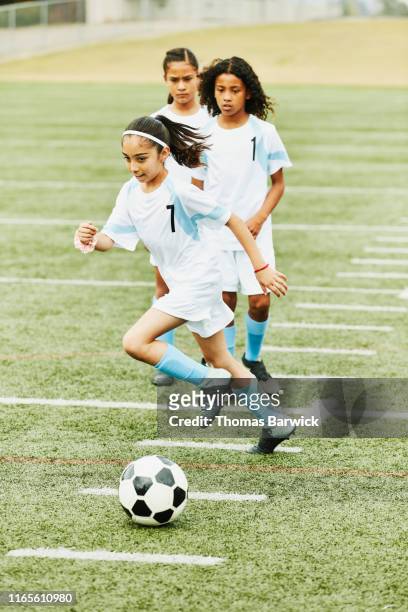 Young female soccer players running warm up drills on field before game